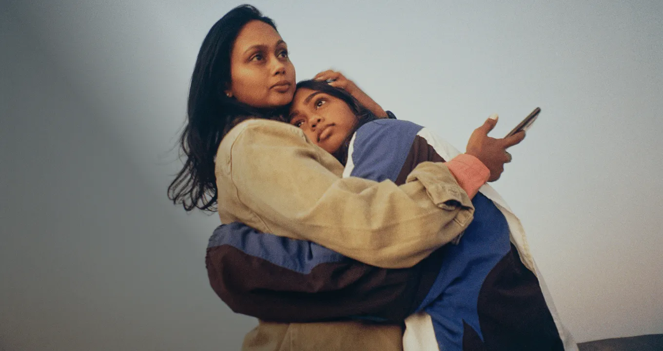 手持行動裝置的母親和女兒相互擁抱